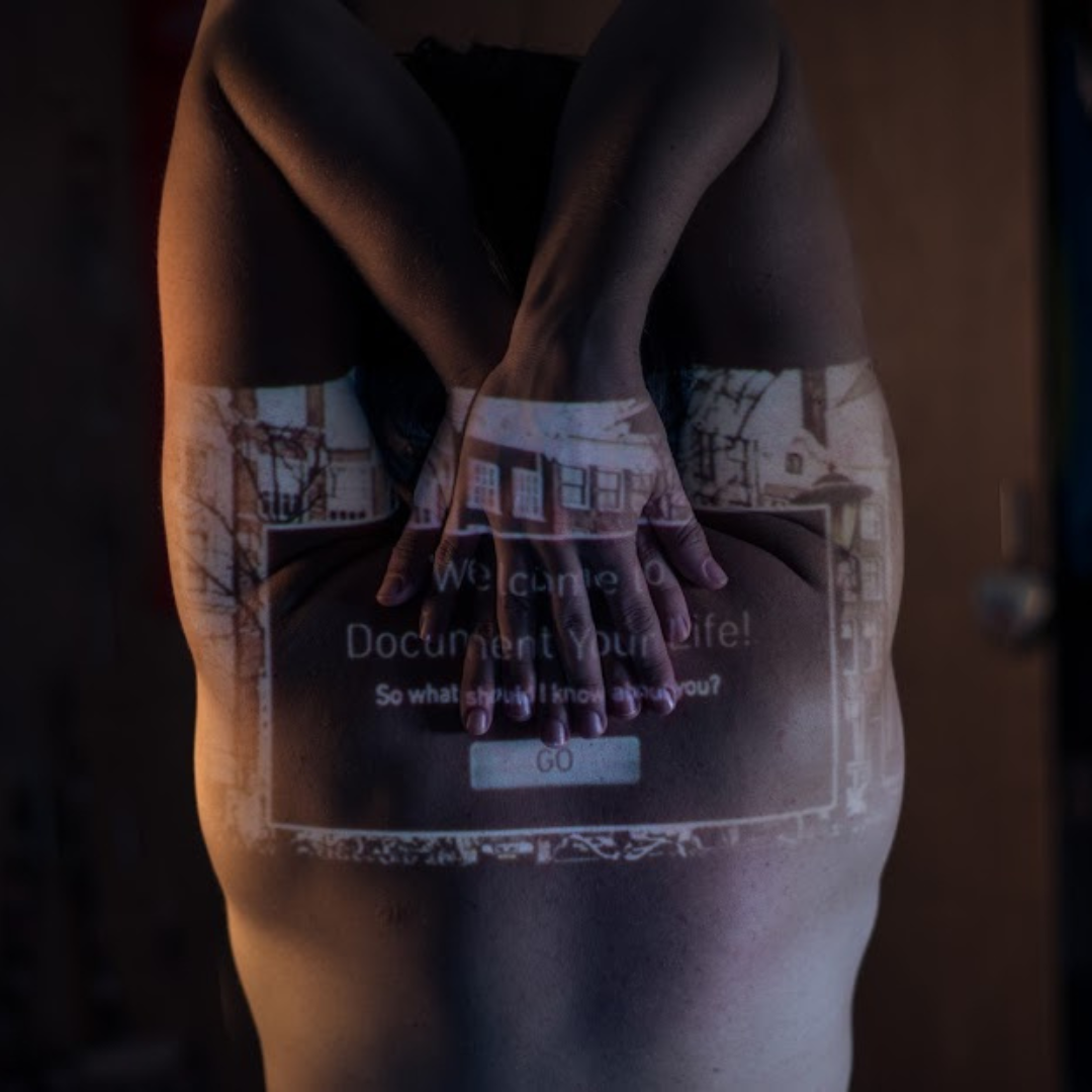 A women reaches for her back with her hands. On her skin is projected a website login page. Text Reads: 'Welcome to Document Your Life! So what should I know about you? Go.'