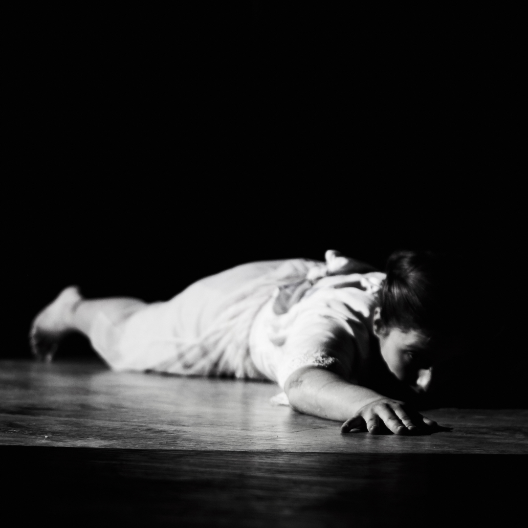 A black and white image of a woman lying on the floor.