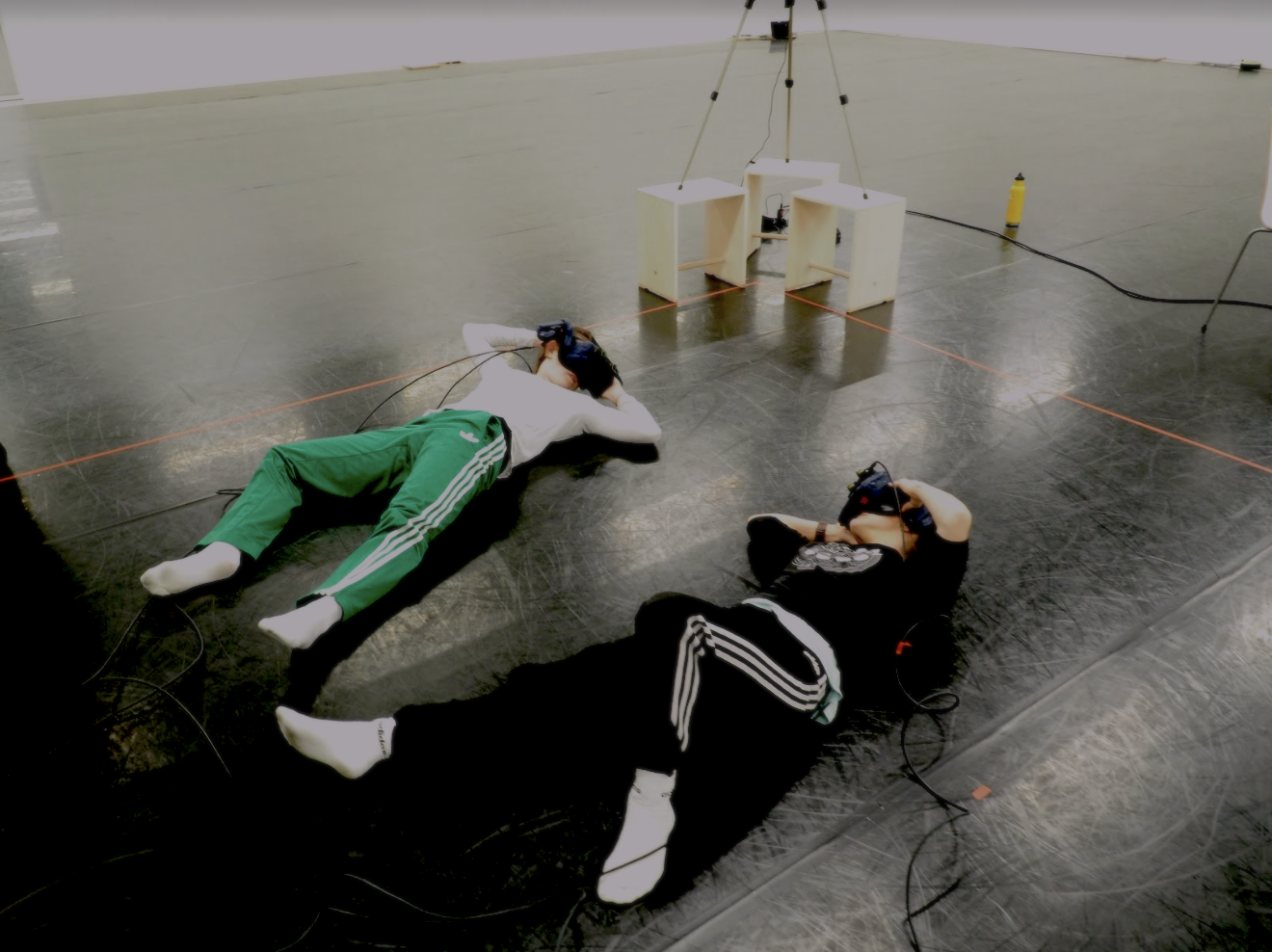 A couple of people laying on the ground with VR headsets on.