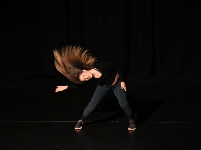 A woman is flipping her hair on stage.