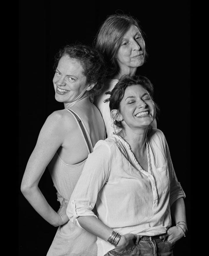 black and white image of three women laughing together on black background that is used for advertising