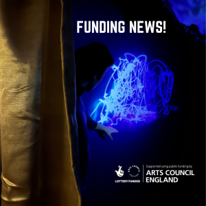 A photo of a person pointing at a projection of a drawn shape. He is inside a dark room. Text Reads: ‘Funding News’ in white and there is the Arts Council Lottery funding logo which says ‘Supported using public funding by Arts Council England. Lottery Funded, Arts Council England’.