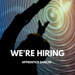 A dancer reached towards their avatar which is projected onto a screen. Text Reads: ‘We’re Hiring Apprentice Dancer’ in white.