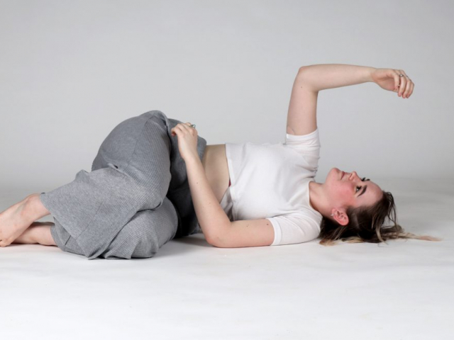a woman laying on her stomach on the floor of a studio shot, posing for a camera