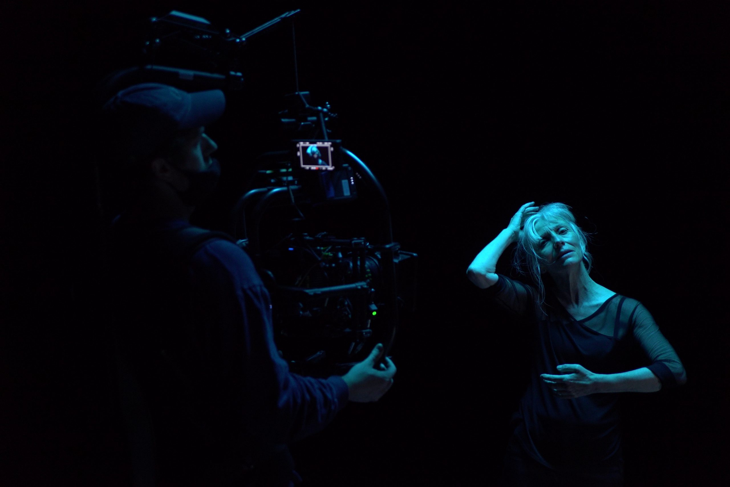 A man and a woman filming in the dark with camera equipment near by while standing next to one another