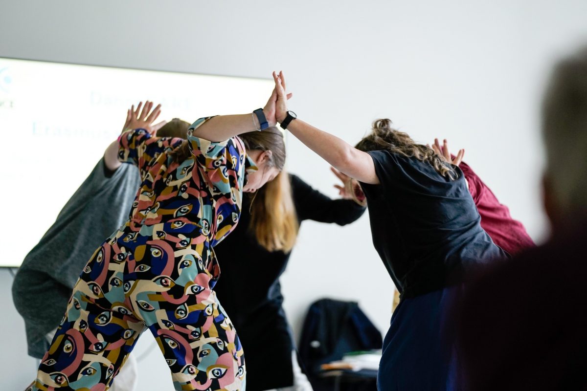 A photo of a group of people pressing their hands together as they lean forward.